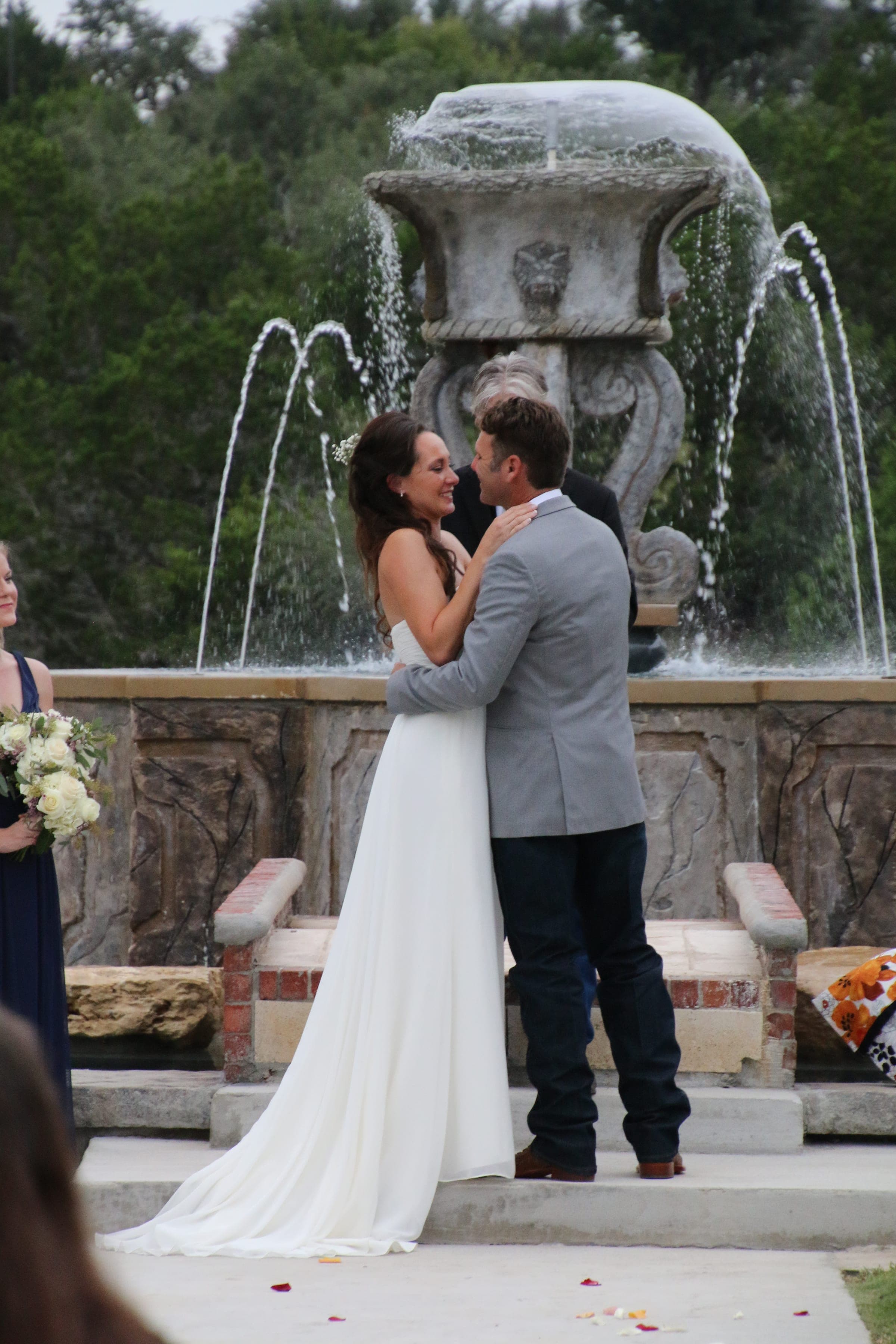 Newlyweds beside the stone fountain wall