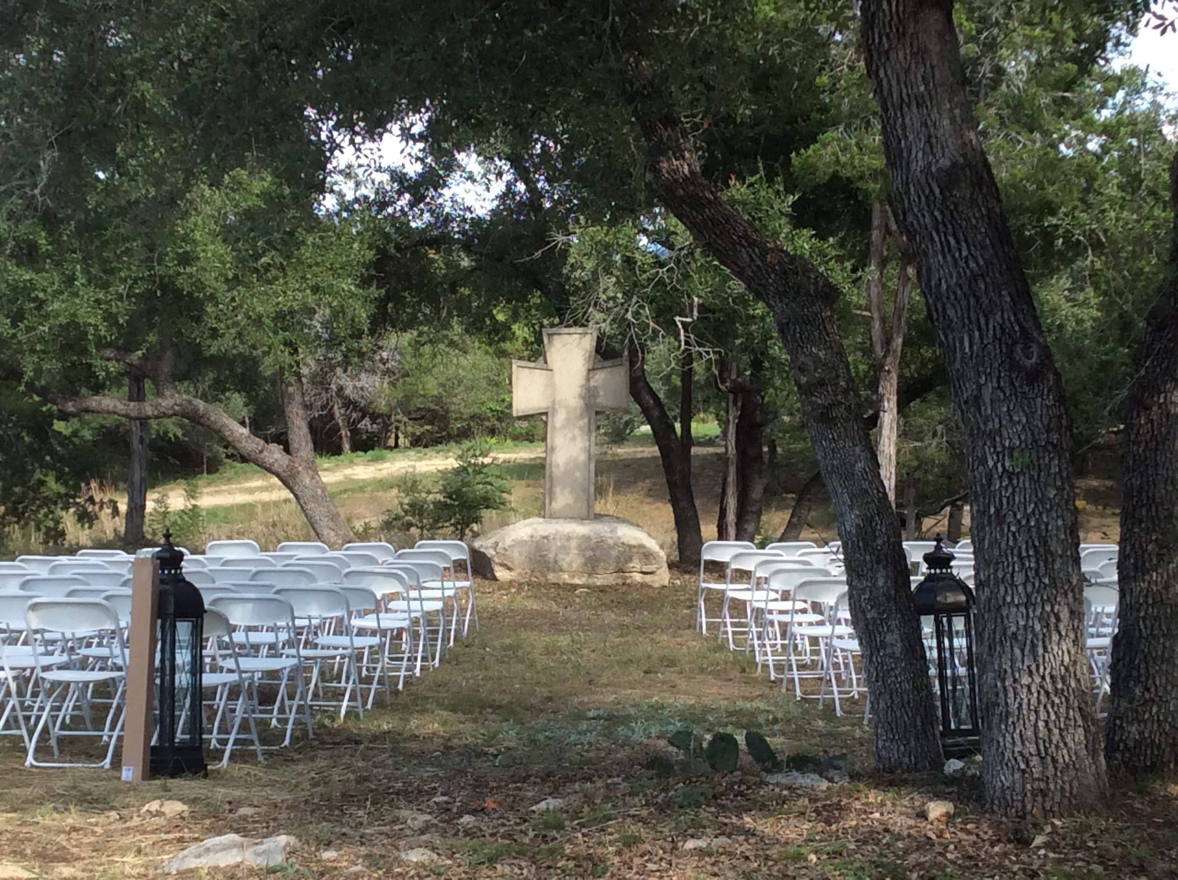 Ceremony aisle set with white folding chairs among the oaks